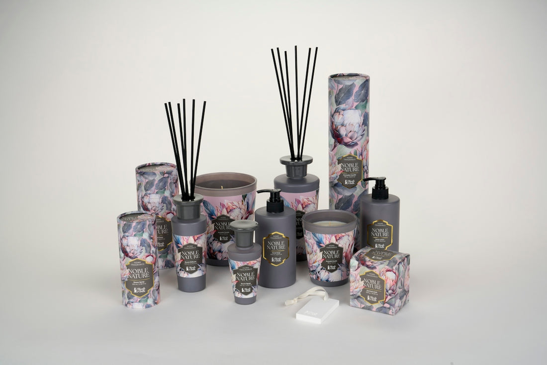 A collection of grey home fragrance products with floral packaging on a white surface