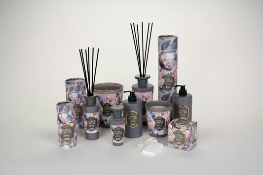 A collection of grey home fragrance products with floral packaging on a white surface